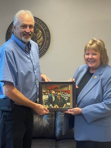 Two people holding a framed pictureAI-generated content may be incorrect.