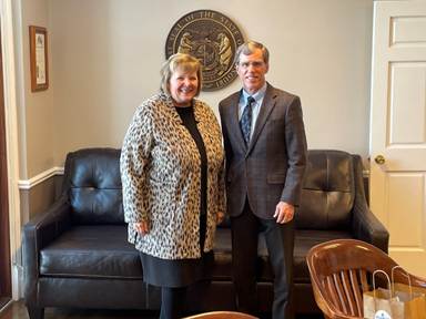 A person and person standing next to each other in front of a couchAI-generated content may be incorrect.