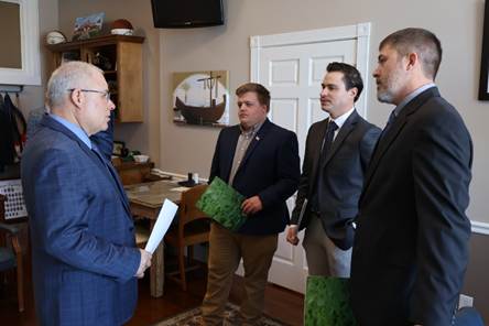 A group of men standing around a tableAI-generated content may be incorrect.